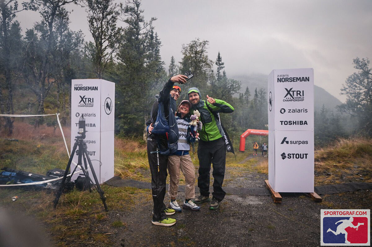 Charlie Sarmiento with his support crew between the Norseman marker signs in the Norwegian fjords